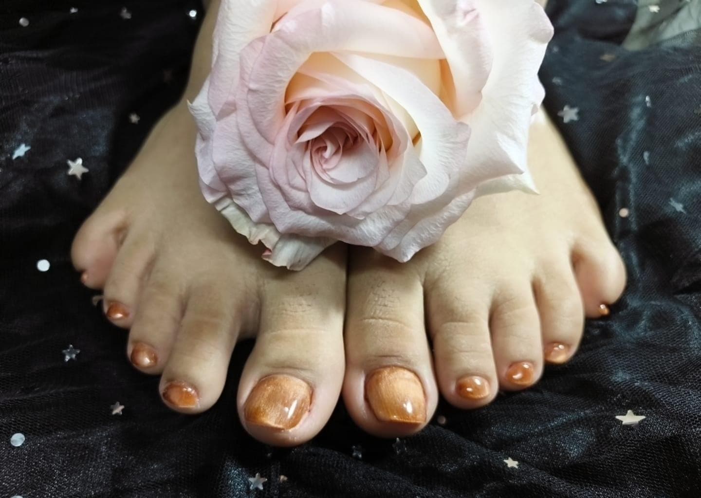 Pedicure cobrizo con una rosa sobre tul con estrellas